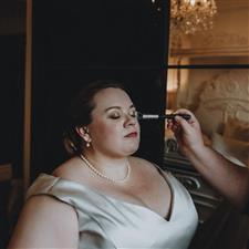 Plus sized bride with pearls has final touchup makeup