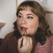 Nude lipstick being applied to bride with gold eyeshadow and eyeliner flick in black