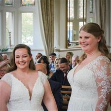 Brides wearing white smile together at the registrar