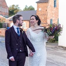 Bride and groom smile at each other while holding hands