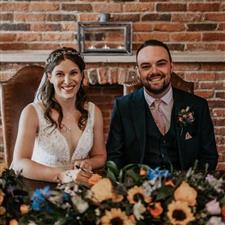 Bride and groom smile at the camera while signing the registrar