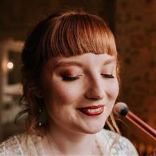 Red haired bride with red lipstick gets blusher applied