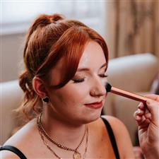 Applying highlighter to red haired bridesmaid