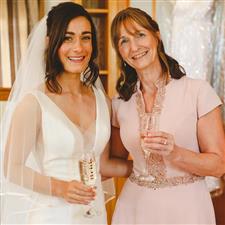 Bride and Mum smile into camera holding champagne flutes