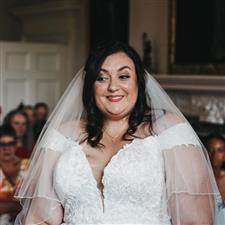 Plus sized brunette bride looks excited off camera during her vows