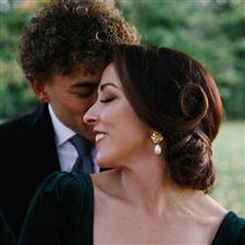 Bride with vintage hair styling in green dress leans into her husband and smiles with her eyes closed