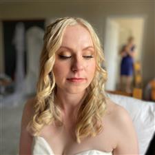 Blonde bride with curled hair wears yellow gold eyeshadow with black winged eyeliner
