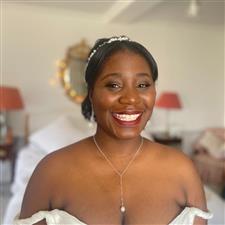 Black bride with dark burgundy lipstick smiles at camera with glowy skin